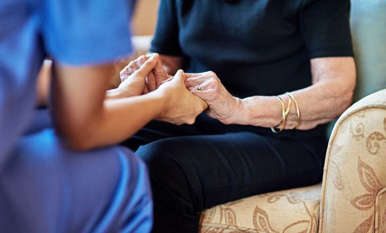 A family reviews legal paperwork with an elderly loved one in a bright, comfortable living room.